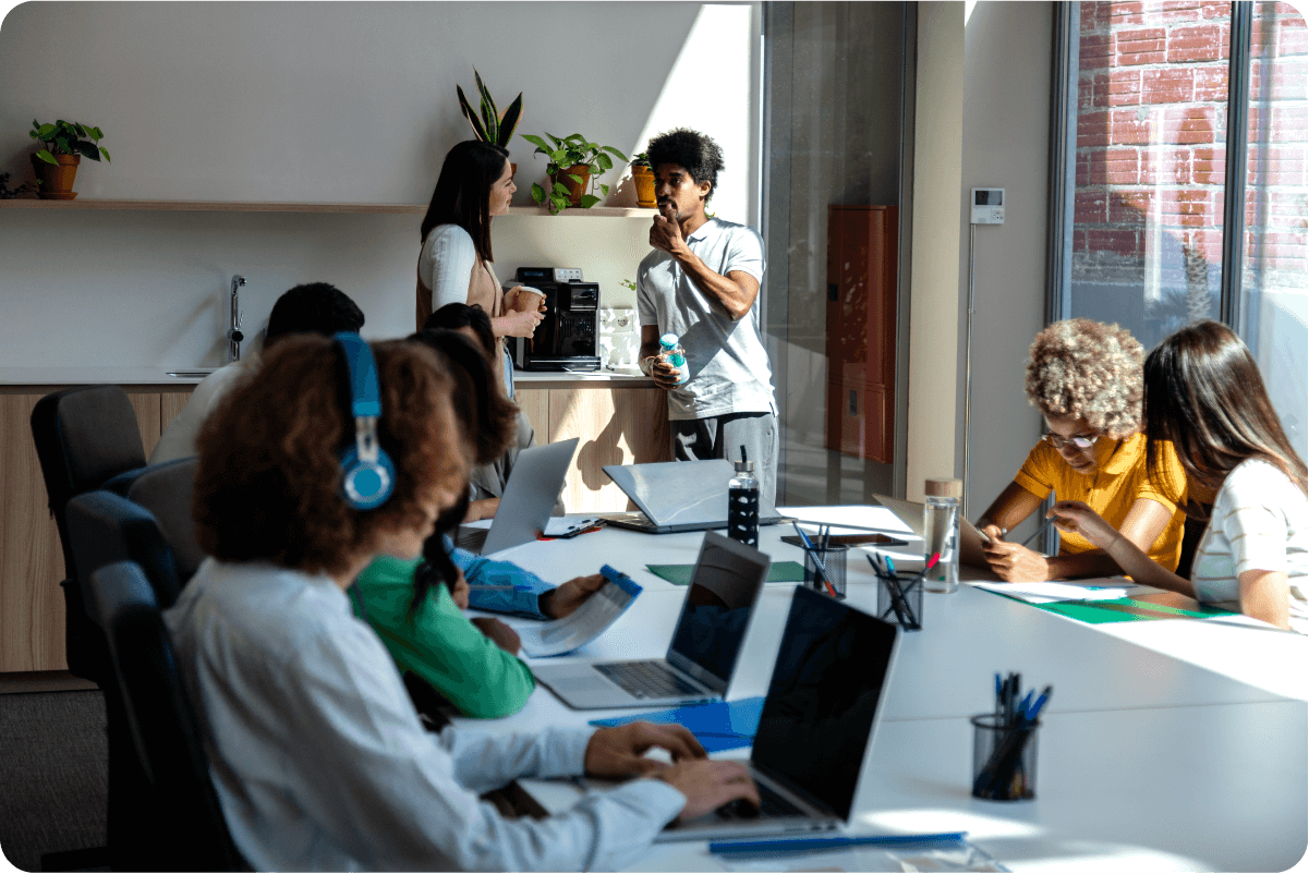 Photograph of several people working in an office with laptops.